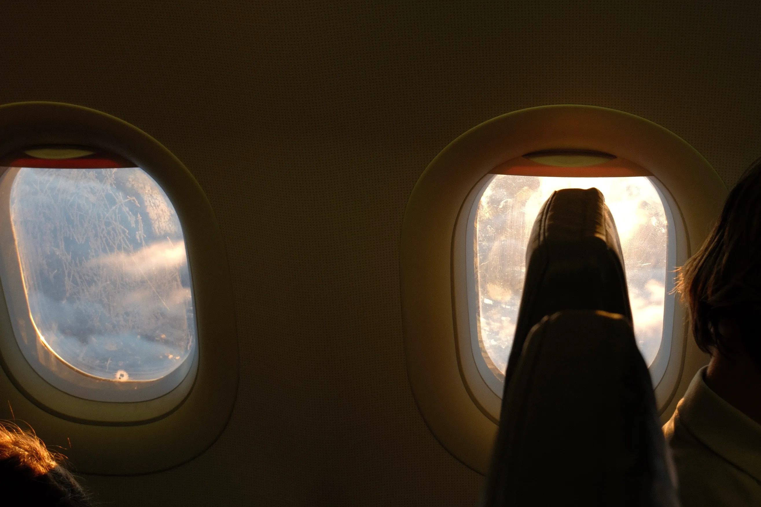 Warm beleuchtete Flugzeugfenster während des Sonnenuntergangs